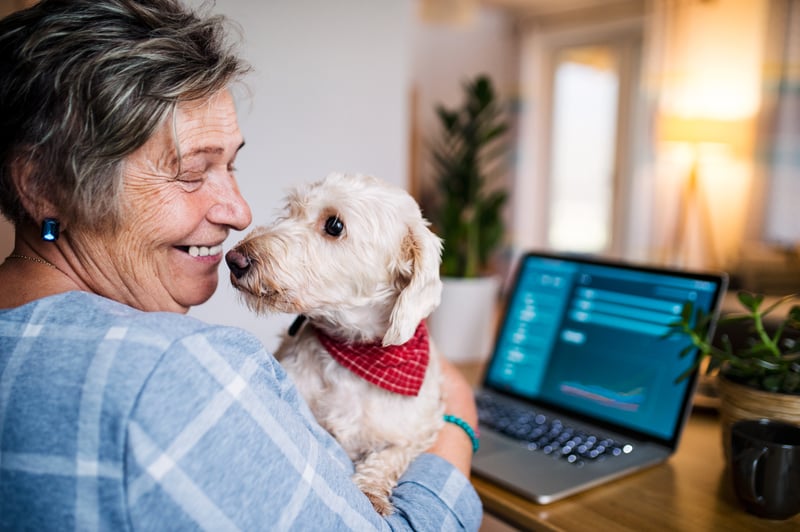Smiling active senior holding a dog while sitting at home