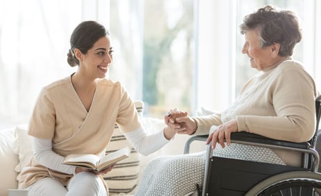 Nurse holding hands with a woman in a wheelchair