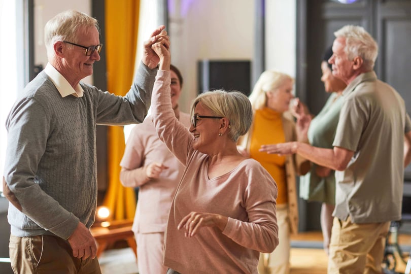 A group of smiling older adults dancing together.